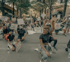 A group of people sitting on the street holding signs at Black Lives Matter marches.