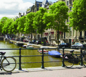 A bike parked on a railing next to a canal in Amsterdam.