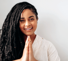 A young woman with dreadlocks positively smiling.