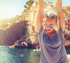 A woman with her arms up in the air, embracing self improvement in front of a city.