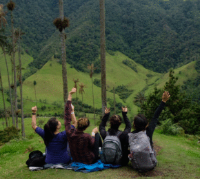 A group of people sitting on top of a hill with palm trees in the background during a Colombia travel.