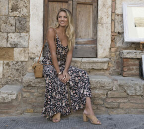 A blonde woman sitting on the steps of an old building.