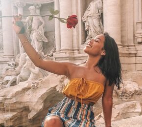 A woman holding a rose at the Trevi Fountain.