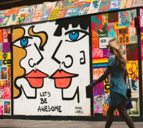 A woman walking past a mural depicting a couple in Great Britain.