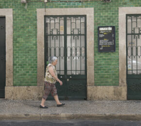 A woman travelling in front of a building.