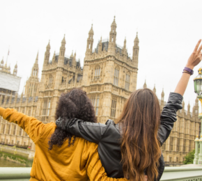 Two young women standing on a bridge overlooking Big Ben in Great Britain.