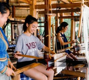 In celebration of International Women's Day, a diverse group of women come together to skillfully work on a weaving loom.