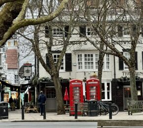 A ted lasso filming location in London featuring trees and a telephone booth.