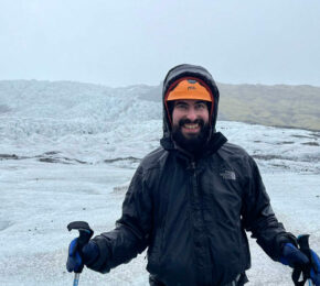 A man is standing in front of a glacier, marveling at the accessibility in Iceland.