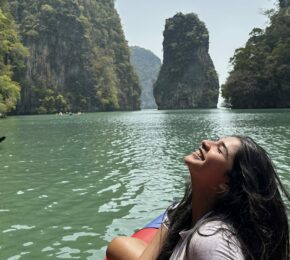 A woman enjoying social travel in Thailand sits peacefully on a red raft, surrounded by the soothing waters.