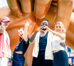 A group of people from South Korea posing in front of a giant hand sculpture.