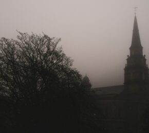 One of the best places to visit for Halloween is a hauntingly beautiful church, its steeple piercing through the dense fog.