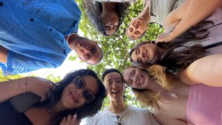 Group of young people in a circle looking down at the camera