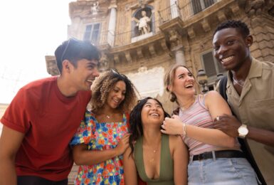 A group of young people laughing in front of one of the best places to visit in Italy.