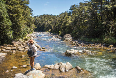 A woman enjoying outdoor activities near a river in New Zealand.