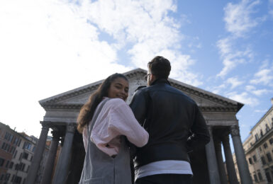 Couple with interlinked arms in front of grand old building