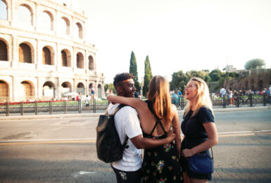 Three friends exploring Europe with Contiki standing in front of the Colosseum in Rome, Italy.