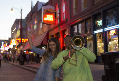 A man and a woman playing music on a city street.