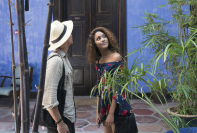 A man and woman representing different cultures standing in front of a blue house.