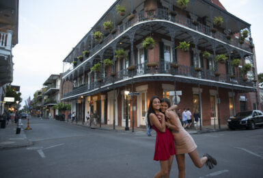 Women smiling at a crossroads with decorative American building