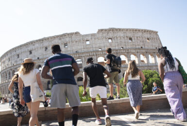 A group of people sightseeing in Rome in front of the colossion.