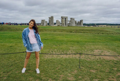 A woman posing in front of Stonehenge during her international exploration.