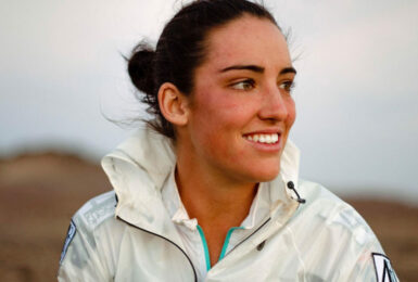 A woman in a white jacket smiling during the 4 deserts race.