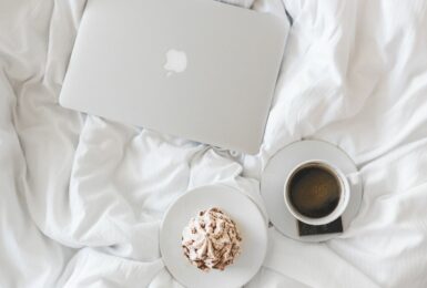 A bed with a laptop and a cup of coffee, envisioning success post-covid.