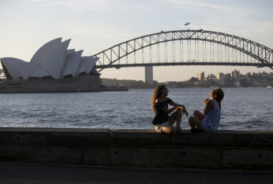 Two women sitting on a wall in front of the Sydney Opera House, job-inspired move.