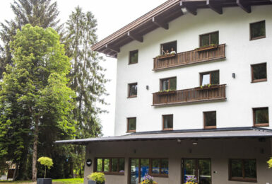 Gasthof Schoneck, a white building with balconies and trees in the background.