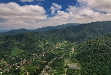 An aerial view of a green valley in Georgia with mountains.