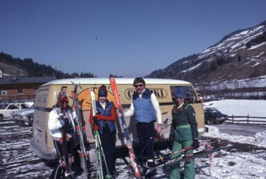 A group of people with skis and a van.