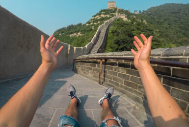 A person with their hands up on the great wall of china.