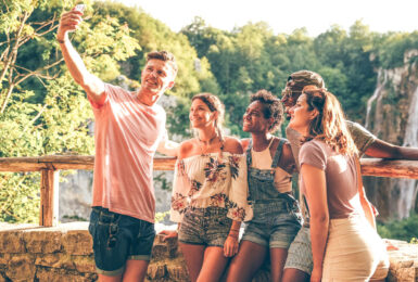 A group of friends taking a selfie in front of a waterfall.