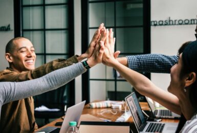 A group of people giving each other high fives in a remote work meeting.