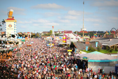 A crowd of people at an amusement park during Oktoberfest.