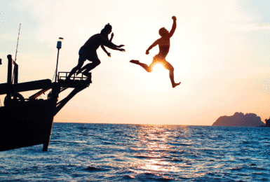 Two digital nomads jumping off a boat in Thailand.