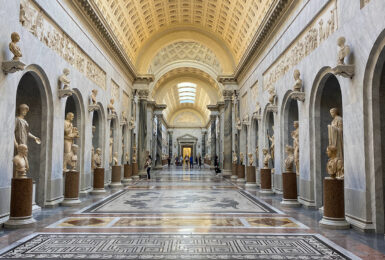 A hallway full of statues in a museum.