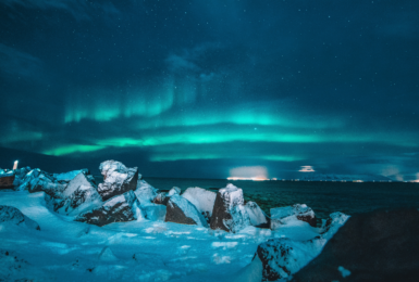 The aurora borealis lights up the sky over a rocky shore during a week in Iceland.