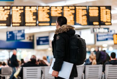 A man with a backpack carrying travel adapters in a train station.