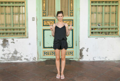 A woman in a black dress standing in front of an old building during her south east Asia travel.