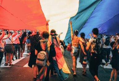 A group of LGBTQ+ individuals holding a rainbow flag in Spain.