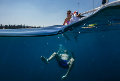 A woman is swimming in the water near a boat.