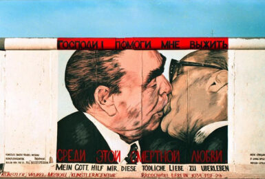 A captivating mural depicting two men kissing skillfully painted on a colorful Berlin wall.