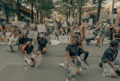 A group of people sitting on the street holding signs at Black Lives Matter marches.