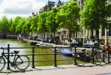 A bike parked on a railing next to a canal in Amsterdam.