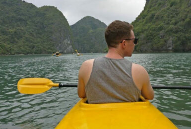 Dom Oliver is paddling a yellow kayak on a body of water.