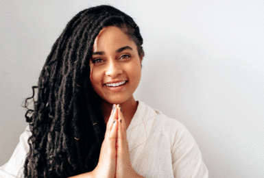 A young woman with dreadlocks positively smiling.