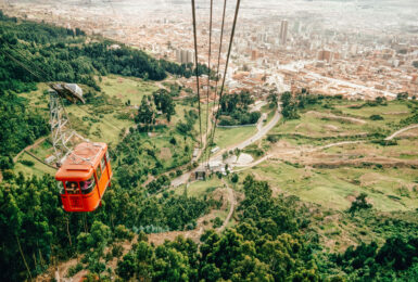 A cable car is flying over a city in colombia.