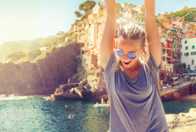 A woman with her arms up in the air, embracing self improvement in front of a city.